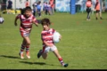 Des enfants jouant au rugby sur un terrain, l'un d'eux s'apprête à passer un adversaire avec le ballon en main